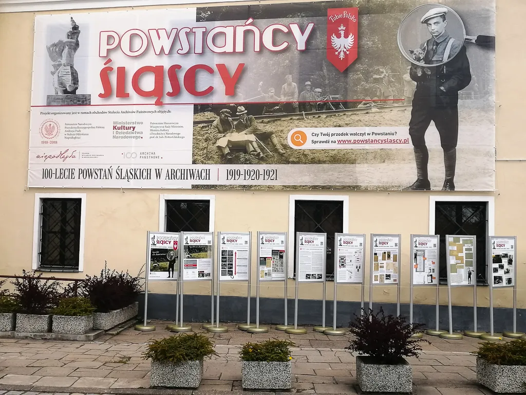 Plansze wystawy ustawione w rzędzie, nad nimi duży baner z tytułem Powstańcy Śląscy.