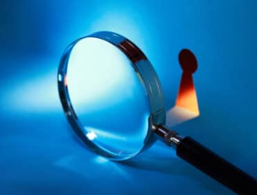 Loupe focalisée sur un petit pion rouge sur fond bleu, symbolisant le contrôle de l'autorité parentale.