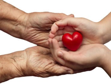 little girl and elderly woman keeping red heart in their palms t