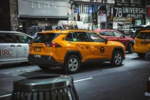 Image-10 shows a yellow taxi SUV parked on a busy city street, surrounded by vehicles and storefronts with bright signs and ads in the background.