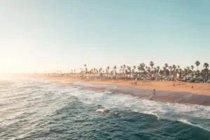 The image-3 shows a wide sandy beach lined with palm trees along the coast, gentle ocean waves under a clear blue sky, and people enjoying the sunny day.