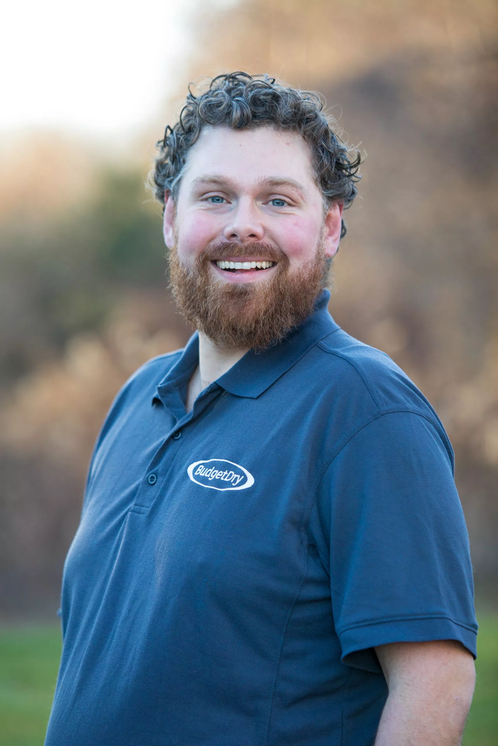 Smiling man in Budget Dry polo shirt, promoting basement waterproofing and foundation repair services.