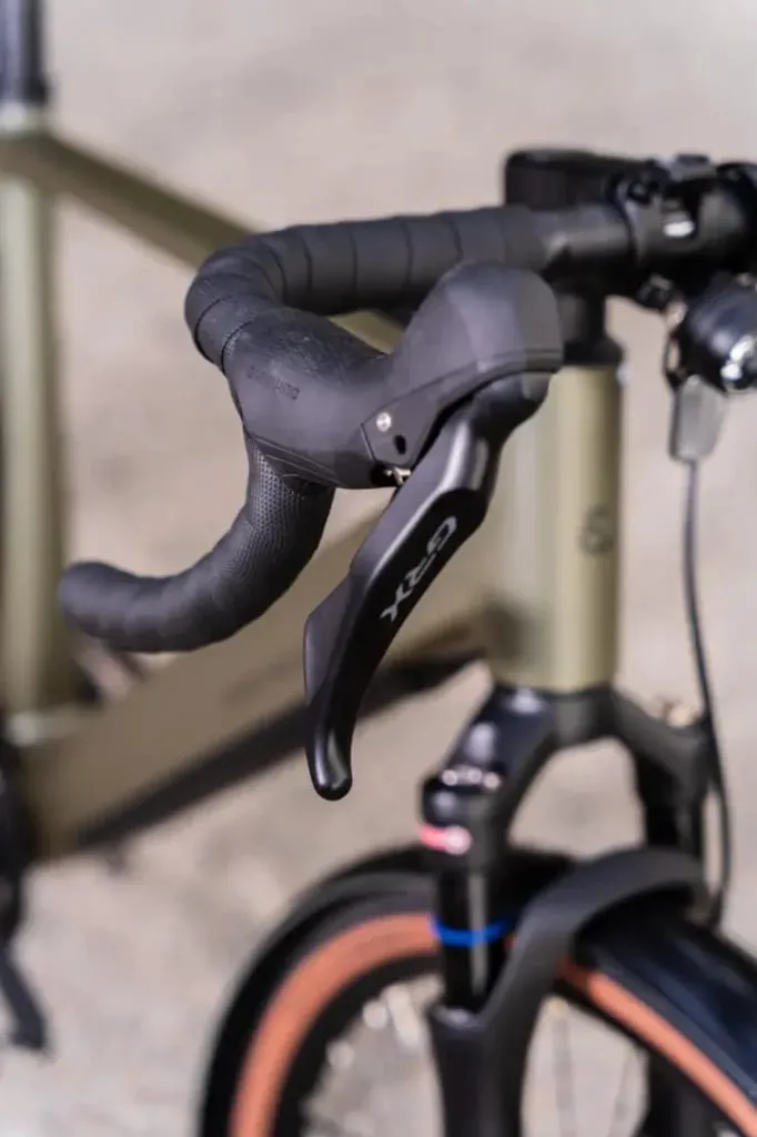 Primer plano del manillar bajo de una bicicleta Riese & Müller, que muestra una palanca de freno GRX y una empuñadura negra texturizada en el versátil modelo UBN Five Commute.