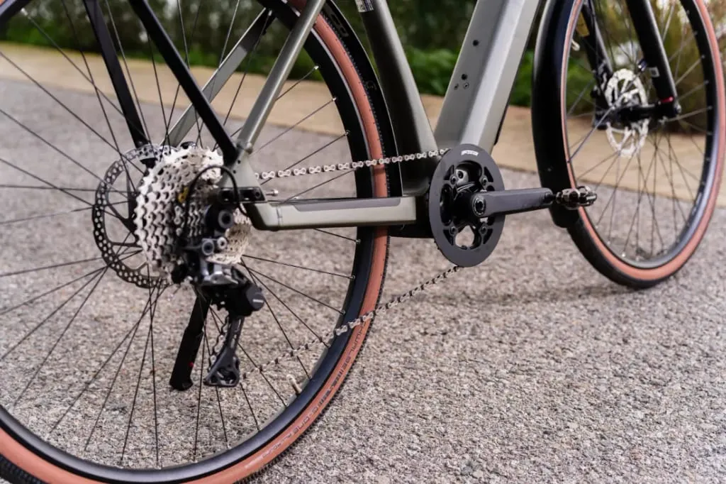Primer plano de la rueda trasera y el sistema de cambio de una bicicleta Riese & Müller UBN Five en una carretera asfaltada.