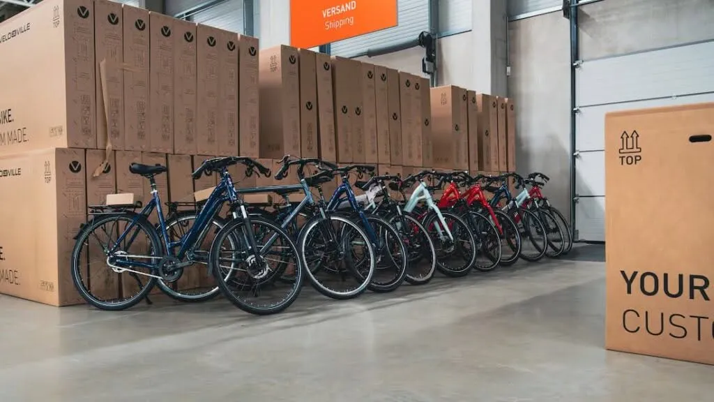 En Valencia, una fila de bicicletas VELO DE VILLE está perfectamente alineada en el almacén junto a grandes cajas de cartón.