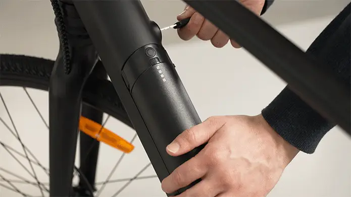 Manos retirando con cuidado la batería negra Kosmos Nova7 del cuadro de una bicicleta eléctrica.