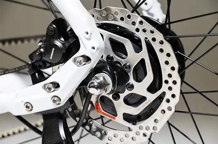 Primer plano de un freno de disco y radios de bicicleta, que muestra los intrincados detalles mecánicos y el acabado metálico, que recuerdan la precisión que se encuentra en la ingeniería de Kosmos Nova7.