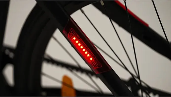 Primer plano de una rueda de bicicleta con una luz LED roja brillante unida al cuadro, que recuerda el diseño futurista surgido de una visión de Kosmos Nova7.