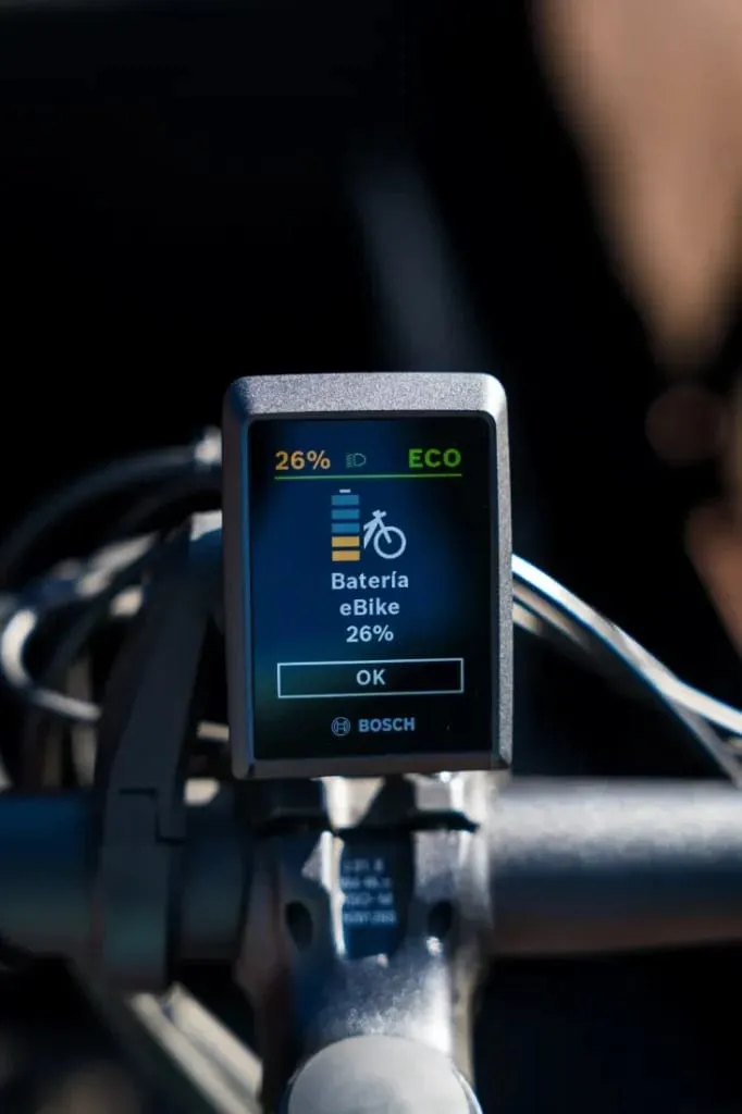 Primer plano de la pantalla de una bicicleta eléctrica Bosch que muestra un 26 % de batería restante en modo ECO en una Riese & Müller Packster2 70 CT Vario, perfecta para familias urbanas que buscan una bicicleta de carga eléctrica eficiente.