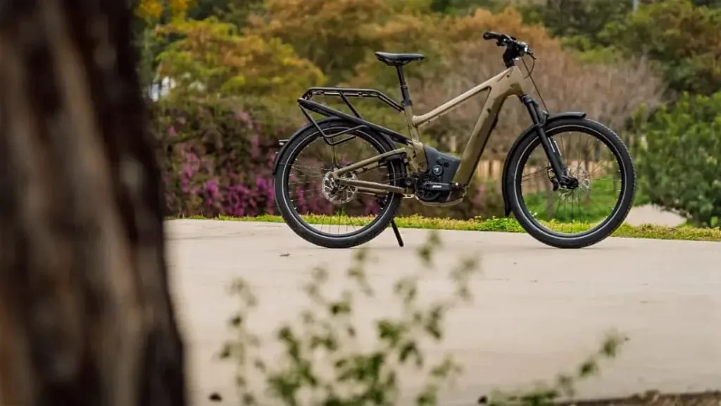 Una bicicleta eléctrica urbana se yergue elegantemente sobre un camino de hormigón, rodeada de un exuberante follaje verde y morado, mostrando tecnología de vanguardia en perfecta armonía con la naturaleza.