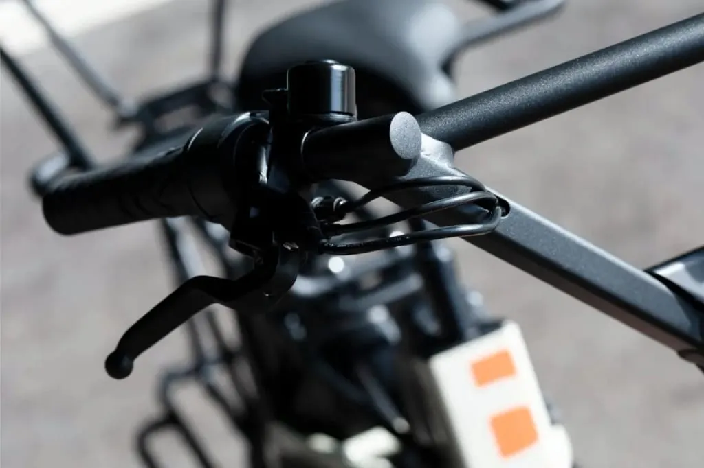Primer plano del manillar de una bicicleta Moustache Lundi 20 Cargo con palanca de freno y componentes borrosos en el fondo.
