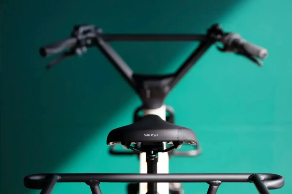 Primer plano del asiento y el manillar de una bicicleta Moustache Lundi 20 Cargo sobre un fondo verde, con "Selle Royal" en el asiento.