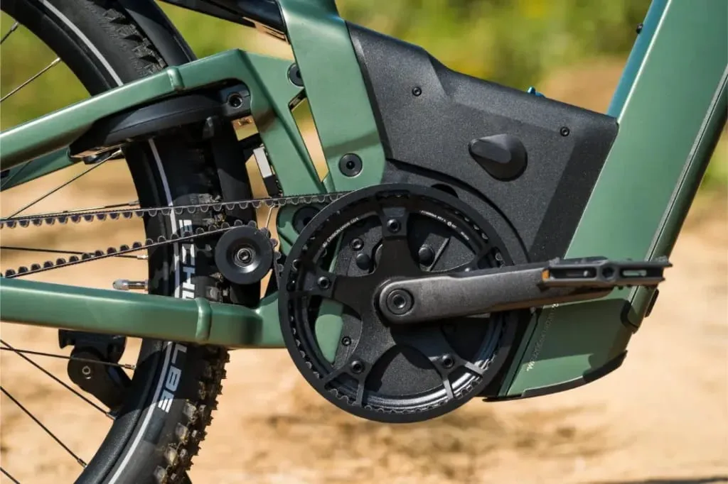 Primer plano del juego de bielas y el motor de una bicicleta eléctrica Riese & Müller Superdelite5 GT Rohloff en un cuadro verde, con un sistema de transmisión por correa, perfecto para tu próxima aventura.