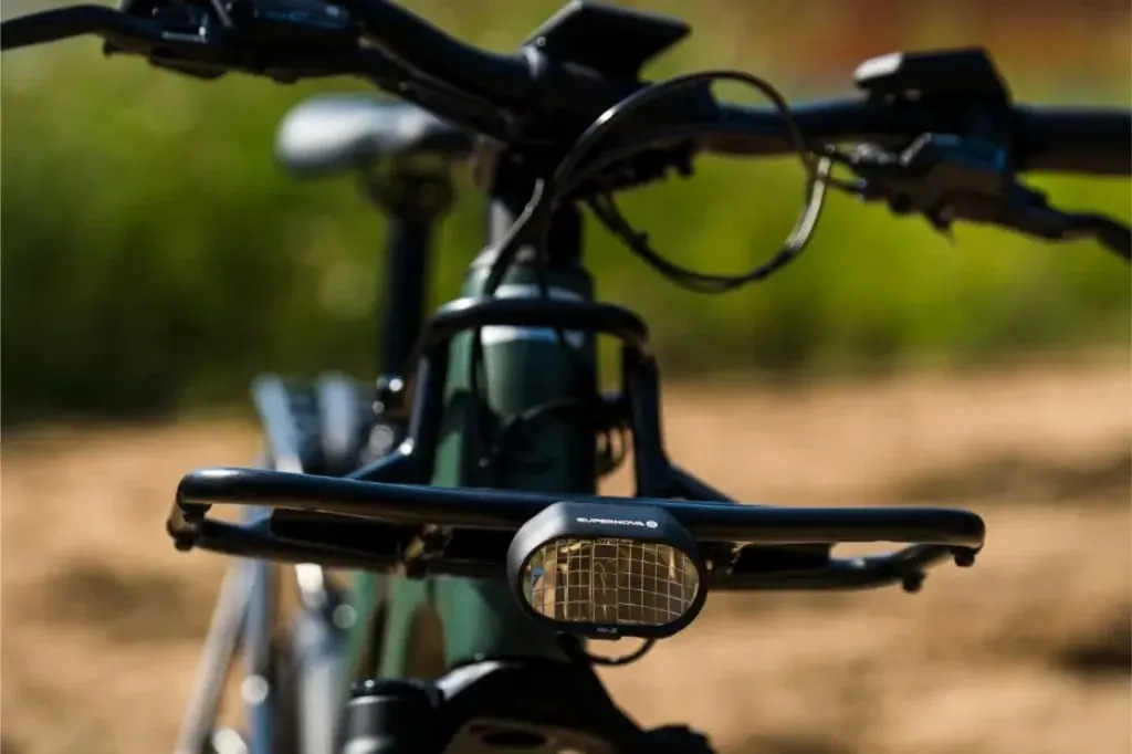 Primer plano del manillar delantero, la luz y la cesta de una bicicleta Riese & Müller Superdelite5 GT, con un fondo exterior borroso.