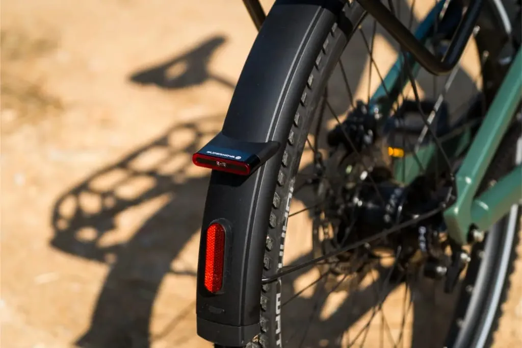 Primer plano de la rueda trasera y el guardabarros de una Riese & Müller Superdelite5 GT con un reflector rojo, luz trasera montada y buje Rohloff integrado.