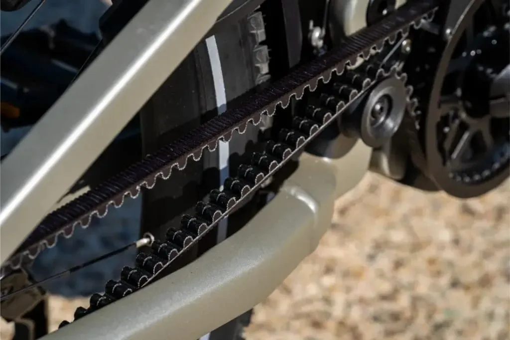 Primer plano del sistema de transmisión por correa de una bicicleta, con la correa dentada y los engranajes -como los que se encuentran en el piñón Homage5 GT de Riese & Müller- para una conducción de paso bajo suave y eficiente.