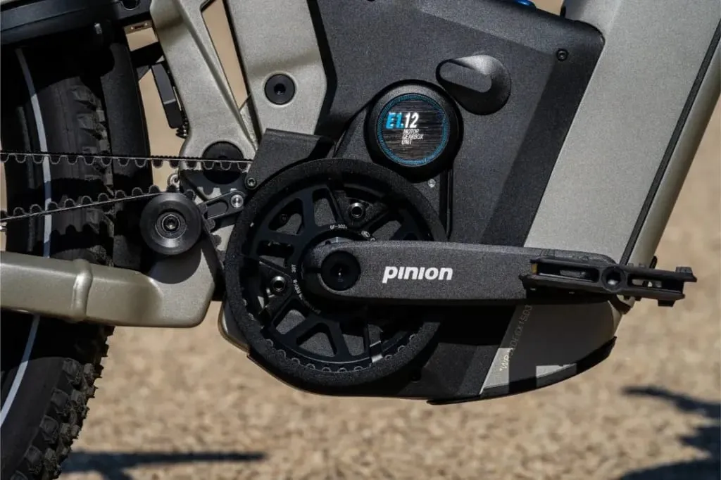 Primer plano de las bielas, el plato y el cambio Pinion de una bicicleta eléctrica sobre una superficie pavimentada, con la Homage5 GT de Riese & Müller con un cómodo diseño de cuadro de paso bajo.