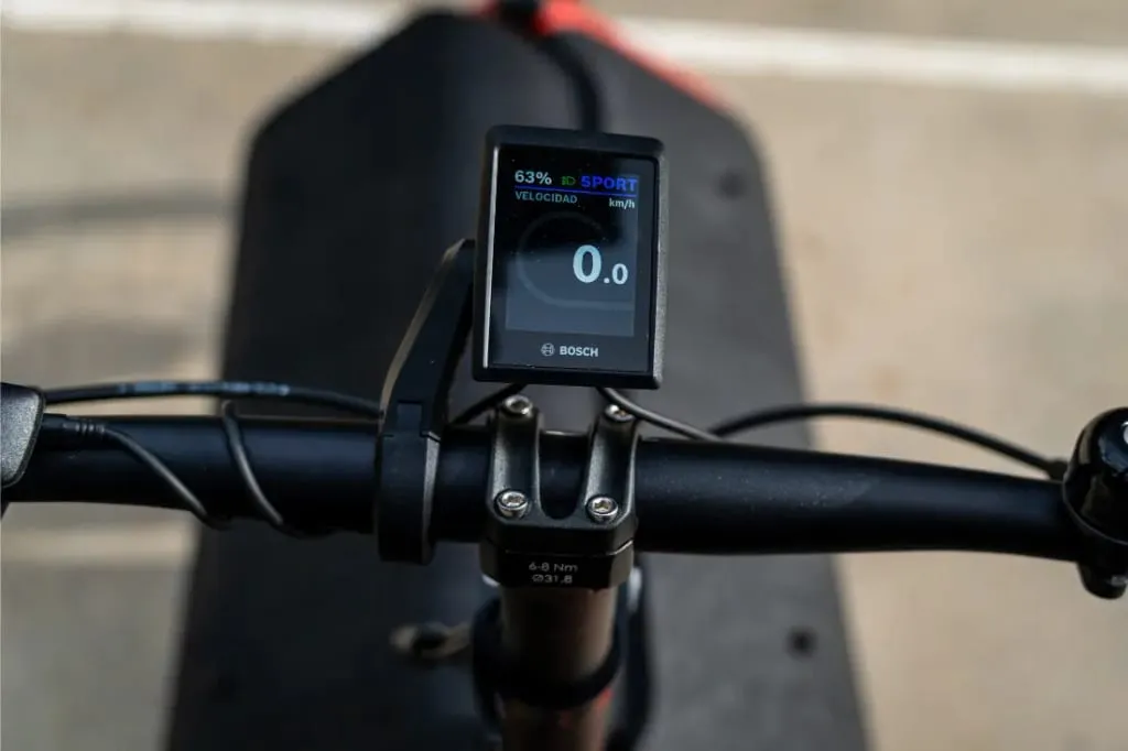 Primer plano de un manillar de bicicleta eléctrica Riese Müller Carrie2 con pantalla Bosch que muestra un 63% de batería y una velocidad de 0,0 km/h, destacando su diseño compacto y sus funciones automáticas.