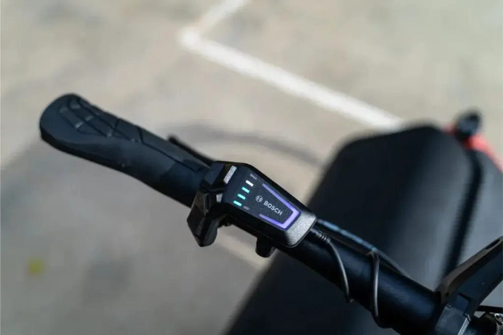 Primer plano del manillar de un scooter eléctrico con una pantalla digital Bosch que muestra los niveles de carga de la batería, similar a la tecnología avanzada que se encuentra en una bicicleta compacta Riese Müller.