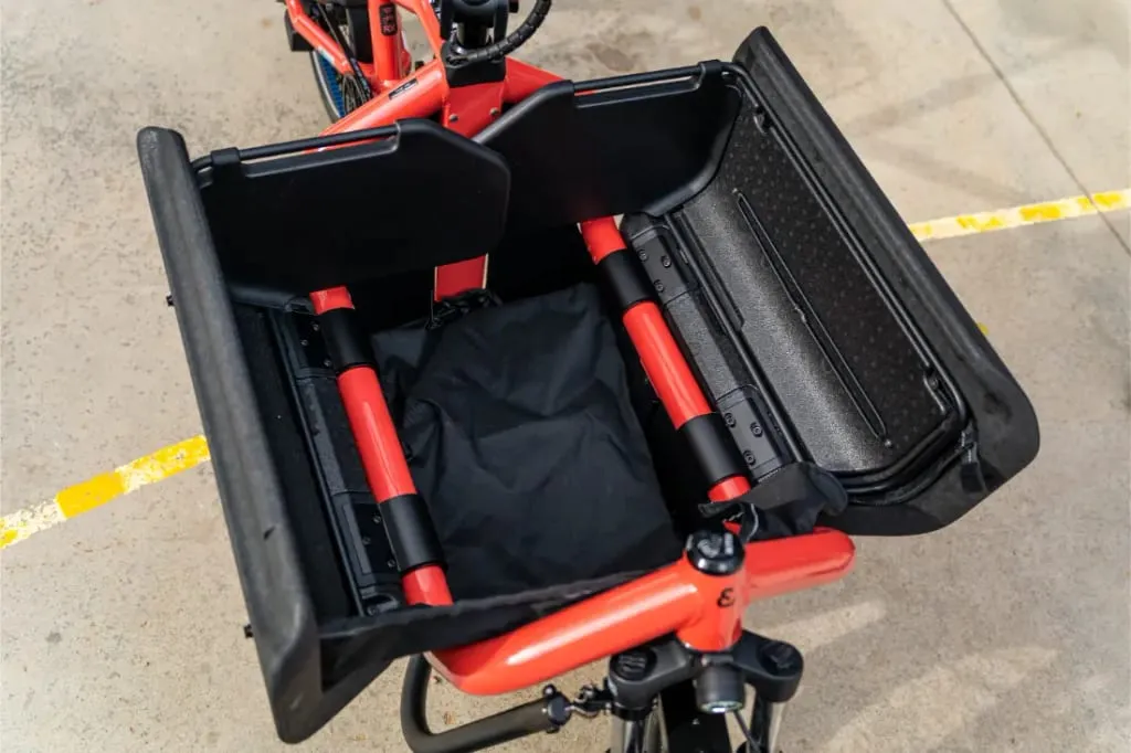 Vista superior de una zona de carga abierta en una bicicleta de carga eléctrica automática Riese Müller Carrie2 con cuadro rojo y tamaño compacto, dentro de un garaje o almacén.