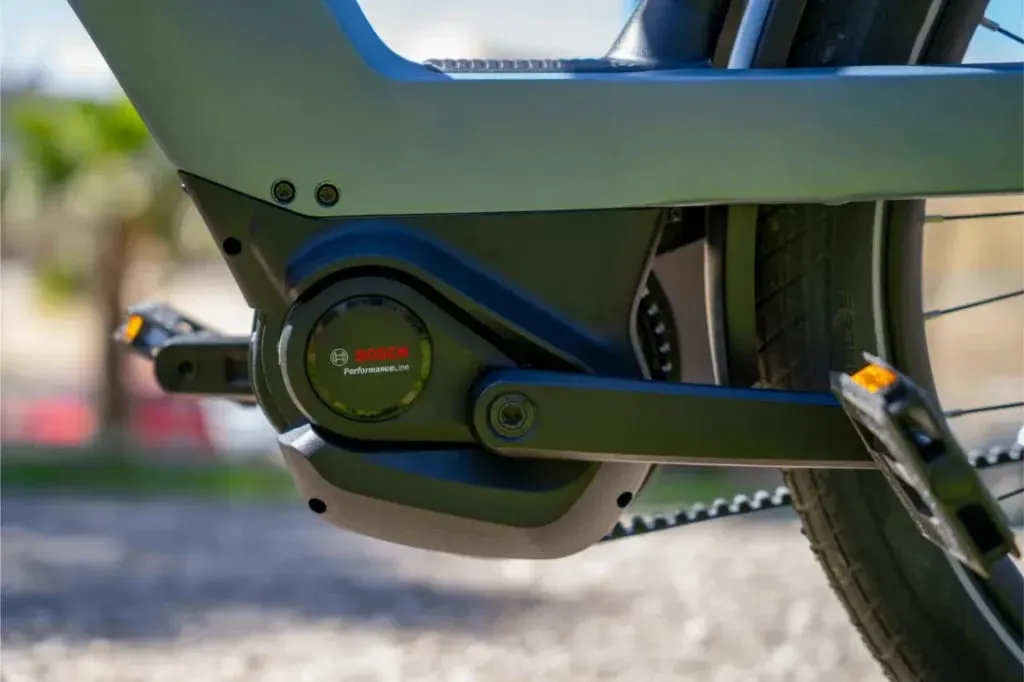 Primer plano de un sistema de motor y pedales de bicicleta eléctrica Bosch en la Nevo5 de Riese & Müller, destacando su silenciosa tecnología CORE para un toque de lujo al aire libre.