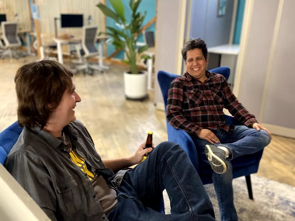 Home-About-Cropped Two coworking members sitting in the lounge area sharing a drink