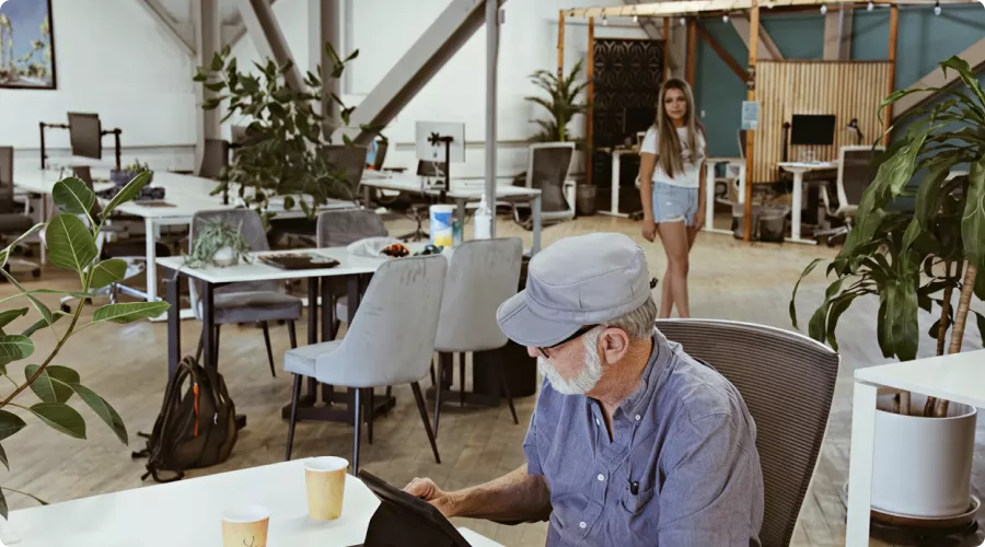 A man working in Cowork + Connect with a woman walking in the background.