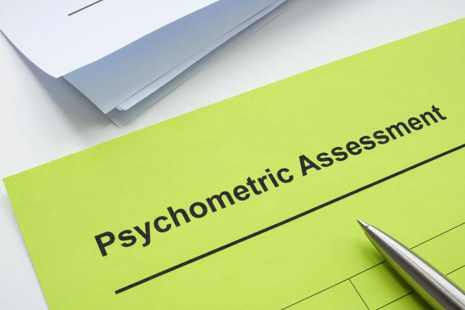 A "Psychometric Assessment" form on bright paper with a pen, representing psychometric testing in progress.