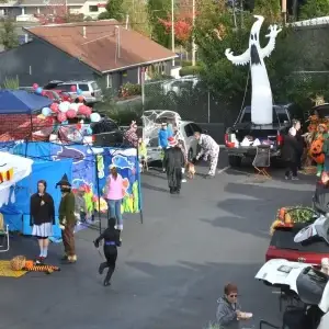 Trunk-or-Treat event with people in costumes, including a giant inflatable ghost on a truck.
