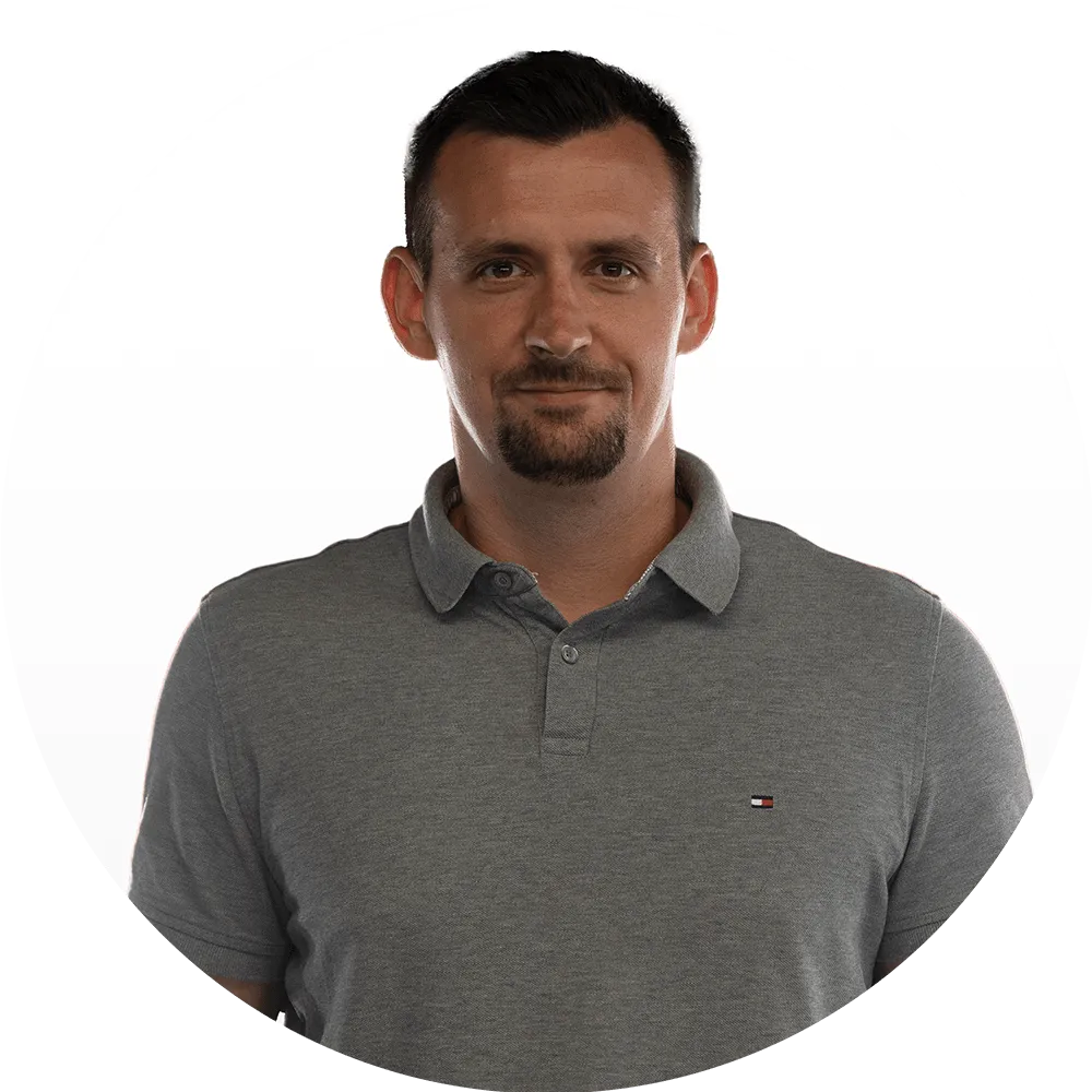 Jakub Żelazek A man with short dark hair and a goatee wearing a gray polo shirt stands against a plain white background, looking directly at the camera with a neutral expression.