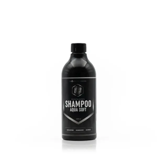Una botella negra de champú con la etiqueta Auto Stuff Shampoo Aqua Soft se encuentra en posición vertical sobre un fondo blanco liso. La etiqueta detalla las características del producto y su capacidad.