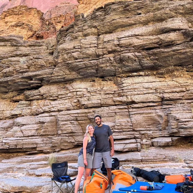 couple on a river trip poses in front of the grand canyon wall