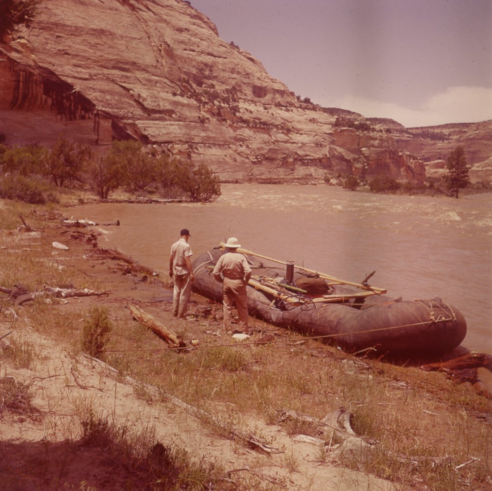 Flashback Friday: History of Motorized Rafts in Grand Canyon 1 two men look at a military surplus pontoon repurposed as a river raft in the 1950s