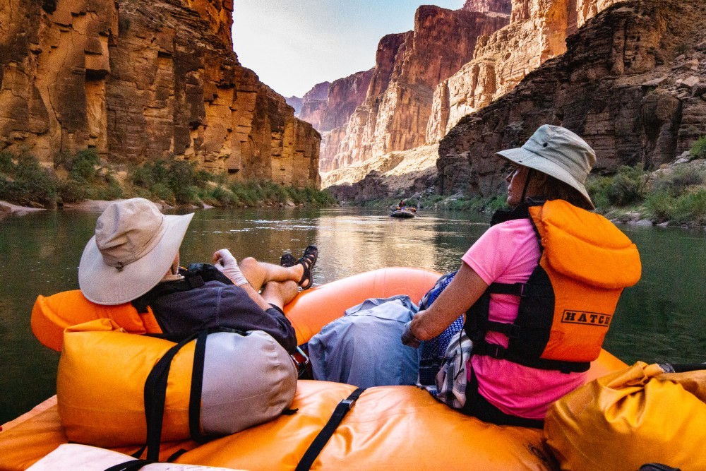 Rafting Grand Canyon by Hatch River Expeditions Two people relax on a river raft enjoying the views of the Grand Canyon