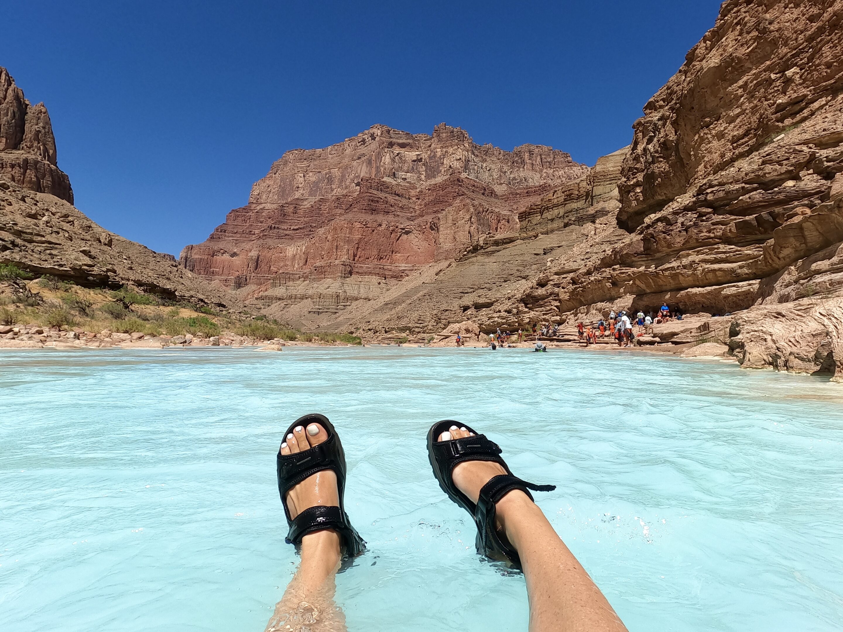 Feet in blue water of Little Colorado River of Grand Canyon Feet in Teva sandals floating in the bright blue Little Colorado River in Grand Canyon