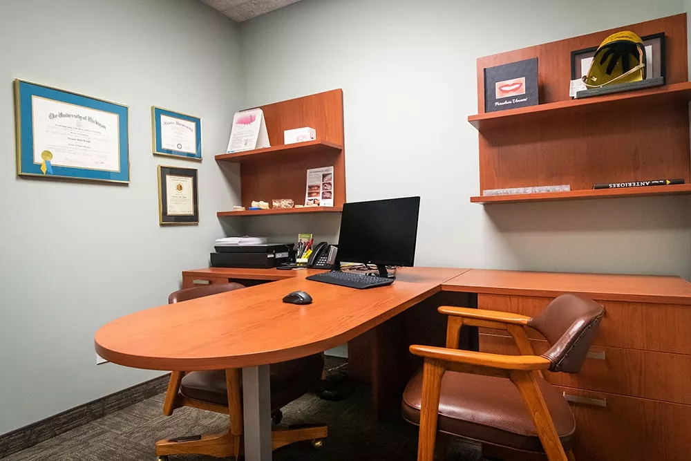 Private consultation office featuring wooden furniture and a computer station at Knight Dental Care in Midland, MI
