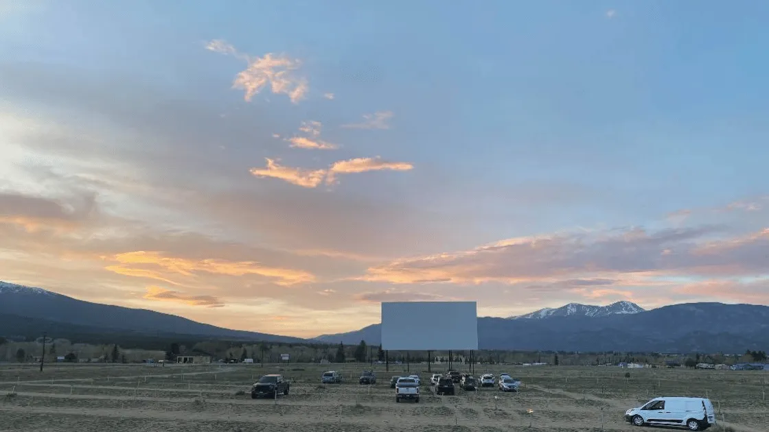 drive-in movies Colorado screen illuminated under starry night sky with cars parked