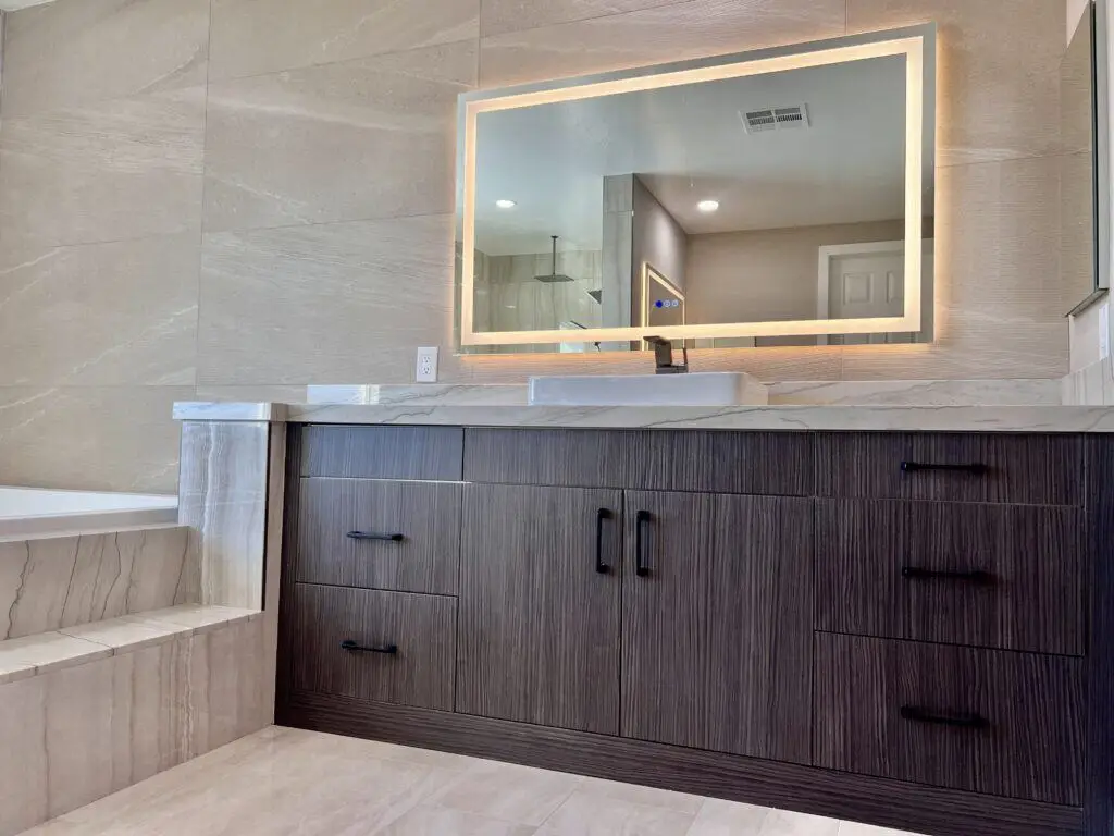 Modern bathroom with a sleek vanity, backlit mirror, and marble tiles.