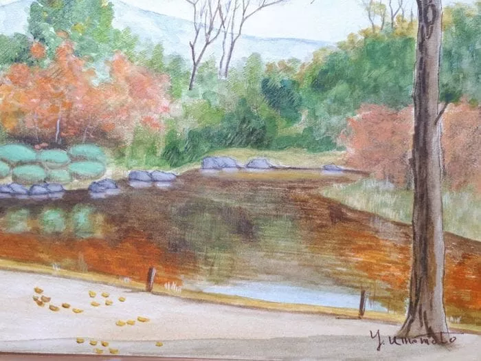 梅本保男による秋の風景画。緑、オレンジ、黄色の紅葉が広がる木々に囲まれた静かな池が描かれています。手前には木の幹と足跡のある道が繊細に描かれています。この作品は、風景水彩画 奈良古都、色紙F6号の静謐な美しさを捉えています。