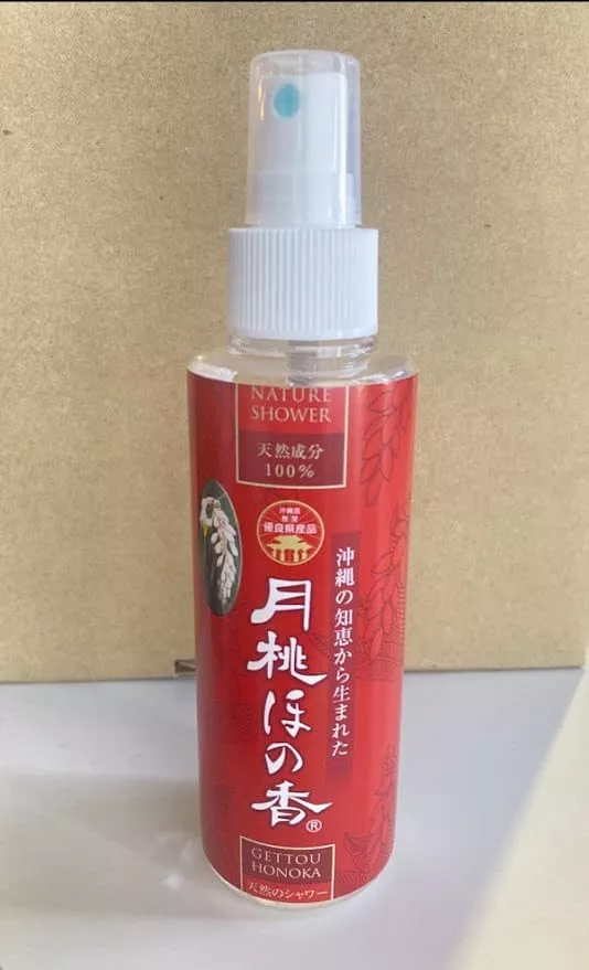 ベージュの背景に「Nature Shower」と書かれた赤いスプレーボトル。白いスプレーノズルとキャップ。.