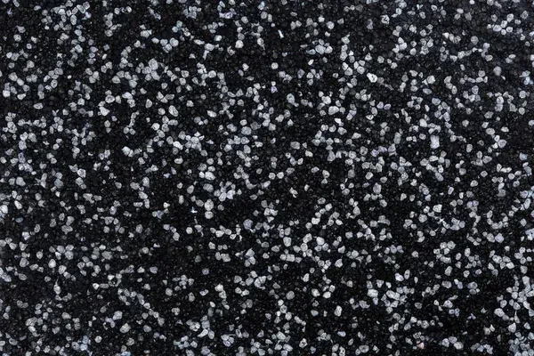 Close-up of coarse white salt crystals scattered over a dark epoxy flooring surface, creating a striking contrast and textured background reminiscent of a stylish Miami garage epoxy floor.