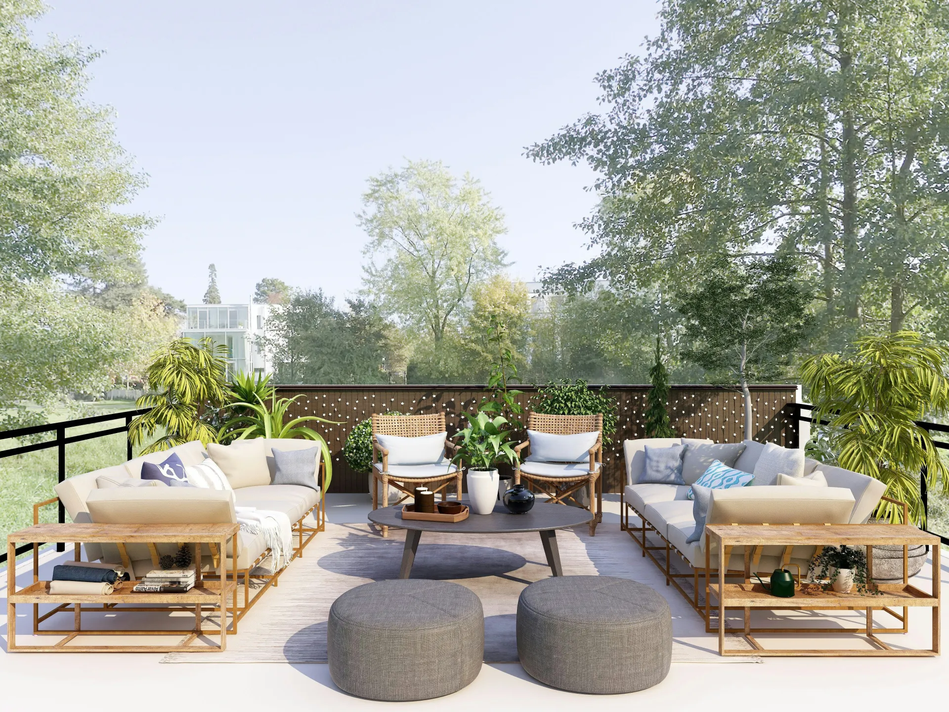 A stylish outdoor patio with cushioned sofas, wicker chairs, green plants, a round coffee table, and two gray ottomans, set on a wooden deck surrounded by trees under a clear sky.