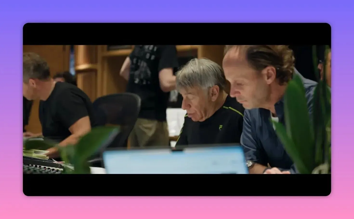 Music department staff leaning over a laptop at a mixing desk reviewing takes