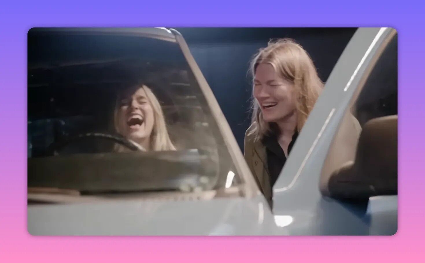 Two cast members laughing together in a parked car, a candid moment of on-set camaraderie