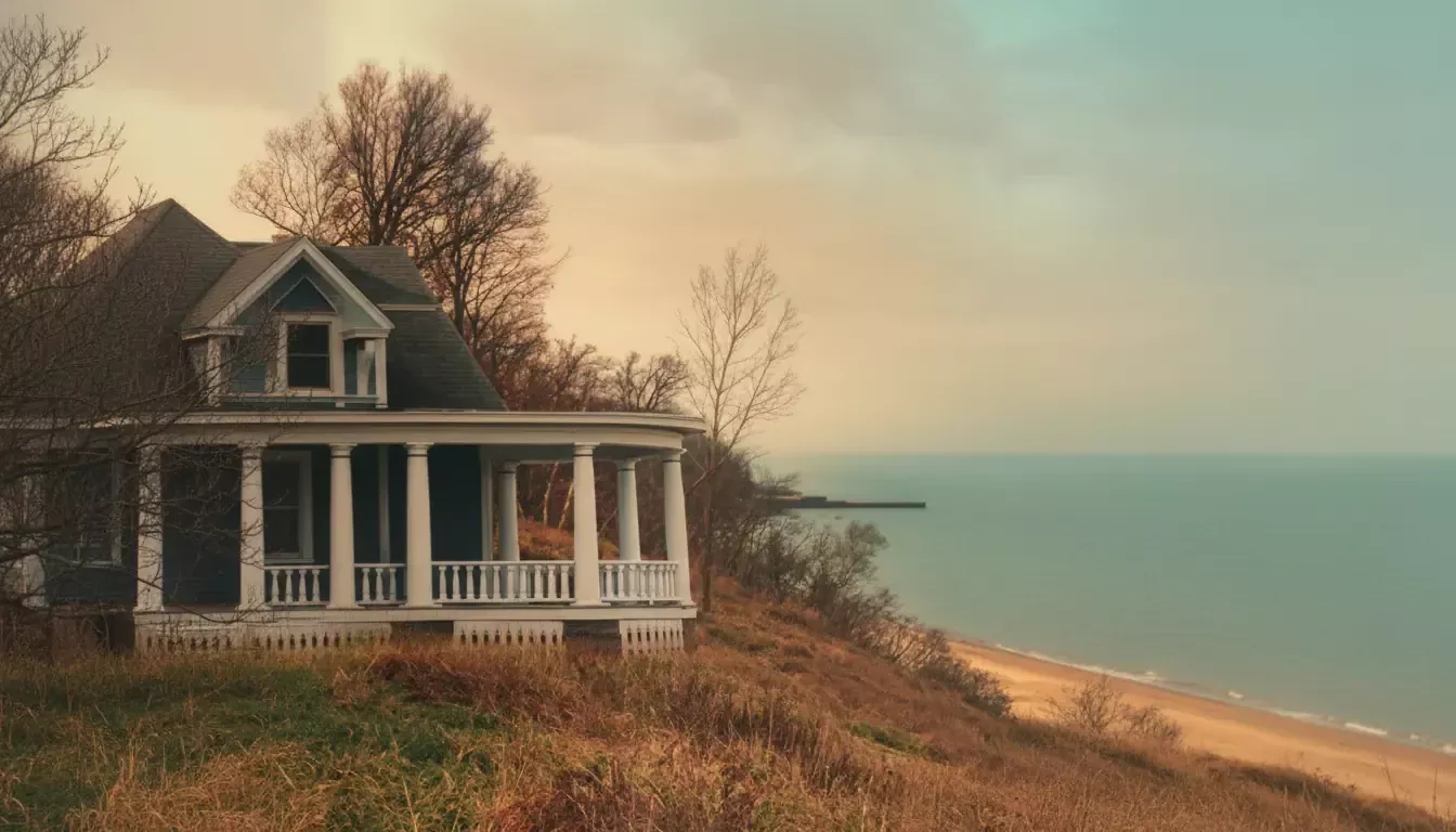 A charming, old-fashioned house with a wraparound porch sits atop a grassy hill, ready for a Thanksgiving Reunion. Leafless trees surround the home, overlooking calm blue water beneath a softly lit pastel sunset sky.