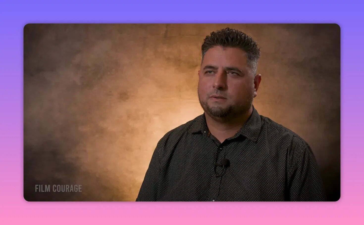 Sharp studio interview shot of a filmmaker against a warm textured backdrop, looking engaged and explaining budgeting and logistics.