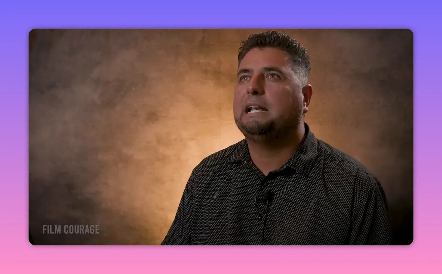 Sharp studio interview image of the filmmaker looking upward with a hopeful, thoughtful expression against a warm textured backdrop.