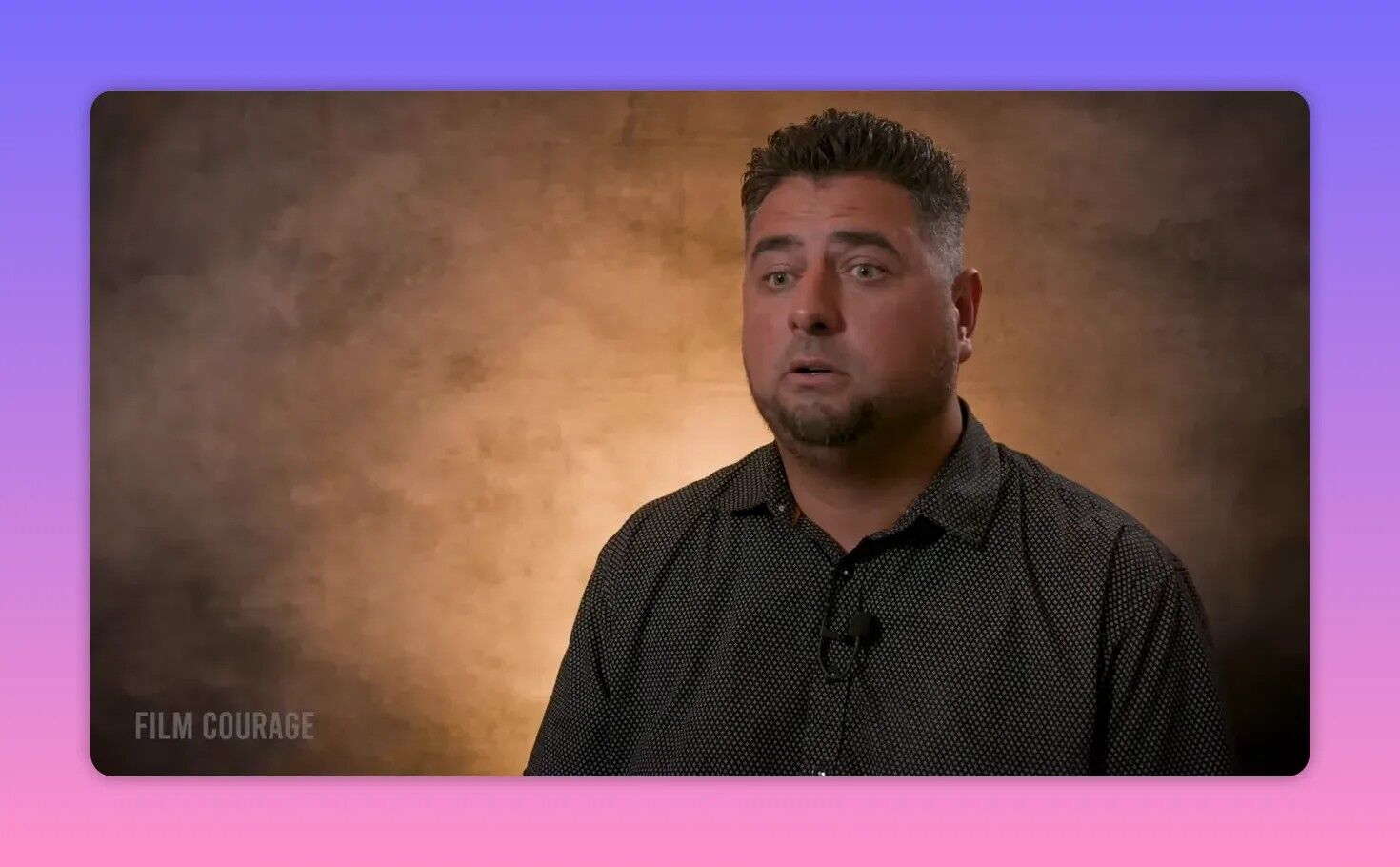 Filmmaker in a clear, high-quality interview frame looking engaged and speaking against a warm textured backdrop.