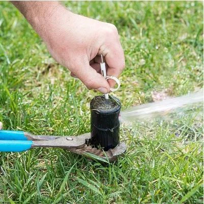 Individual using pliers to open a hose, showcasing skills in irrigation and sprinkler maintenance.