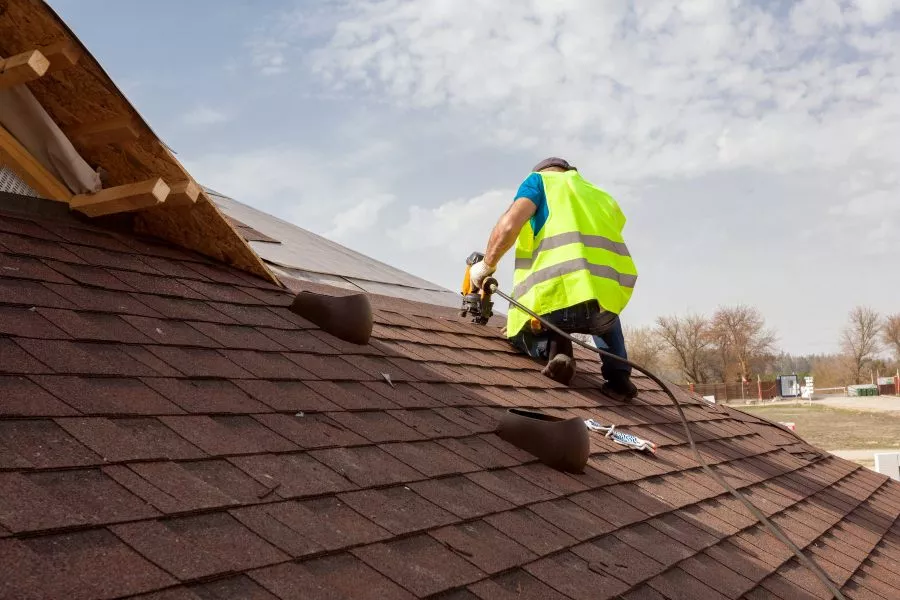 Roofer repairing shingles on roof
